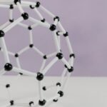 Close-up of a geometric molecular structure model against a pastel background.